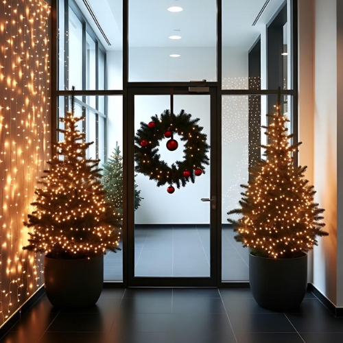 Corporate office entrance decorated with minimal wreath, potted evergreens, and warm white lights for Christmas.