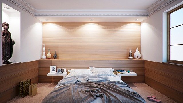 Modern bedroom interior with a neatly made bed, soft neutral bedding, warm lighting, and minimal decor creating a calm and cozy atmosphere