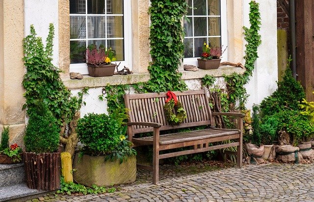 Wooden garden bench placed along a landscaped front yard pathway, adding charm and seating to front of the house landscaping ideas