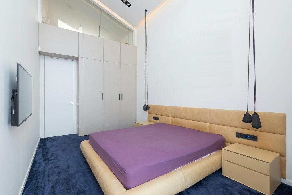 "Modern bedroom interior with upholstered bed, wooden side tables, and decorative lighting accents