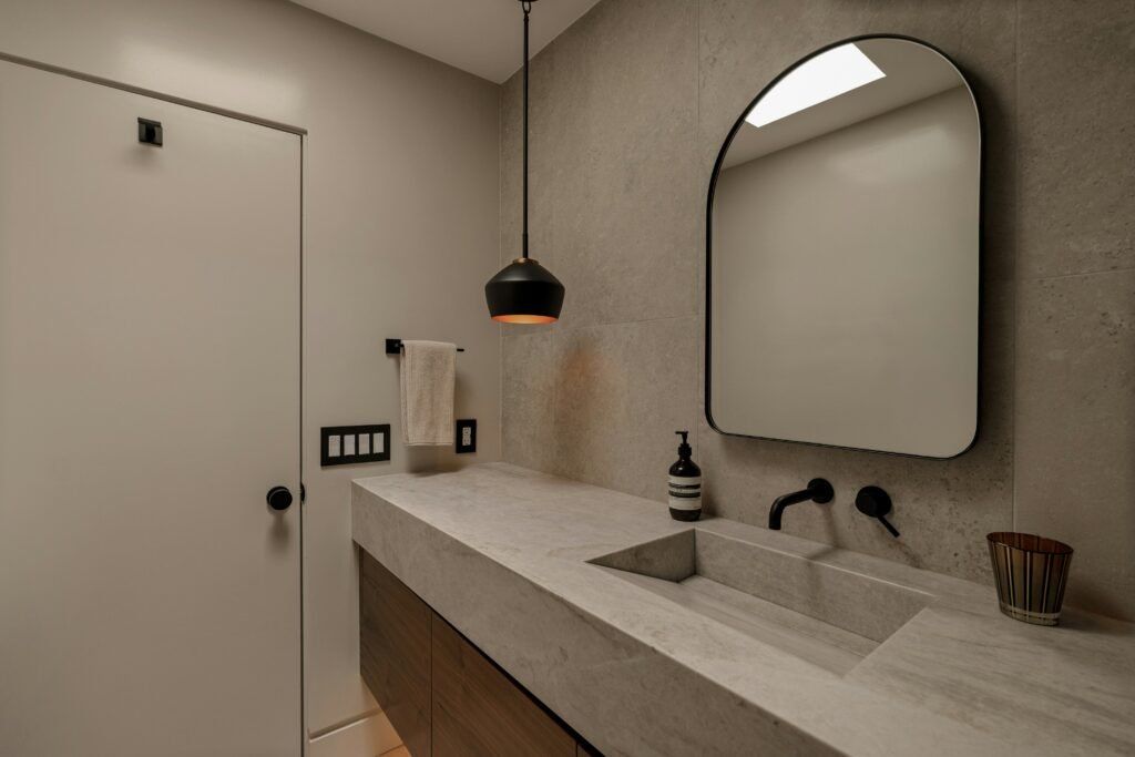Elegant bathroom decorations with double sink vanity, large framed mirror, neutral tiles, and stylish lighting fixtures.