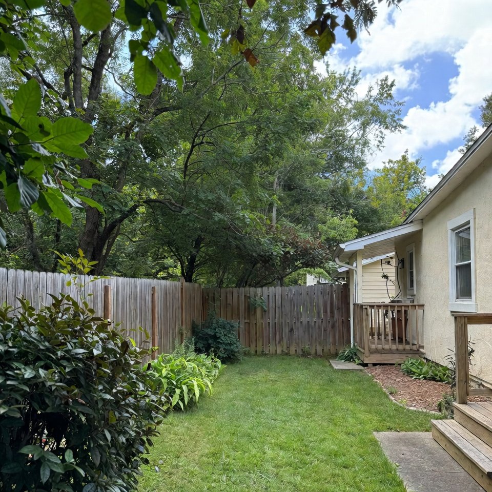 Backyard of a typical USA home with green lawn, wooden deck, outdoor seating, and surrounding fence.