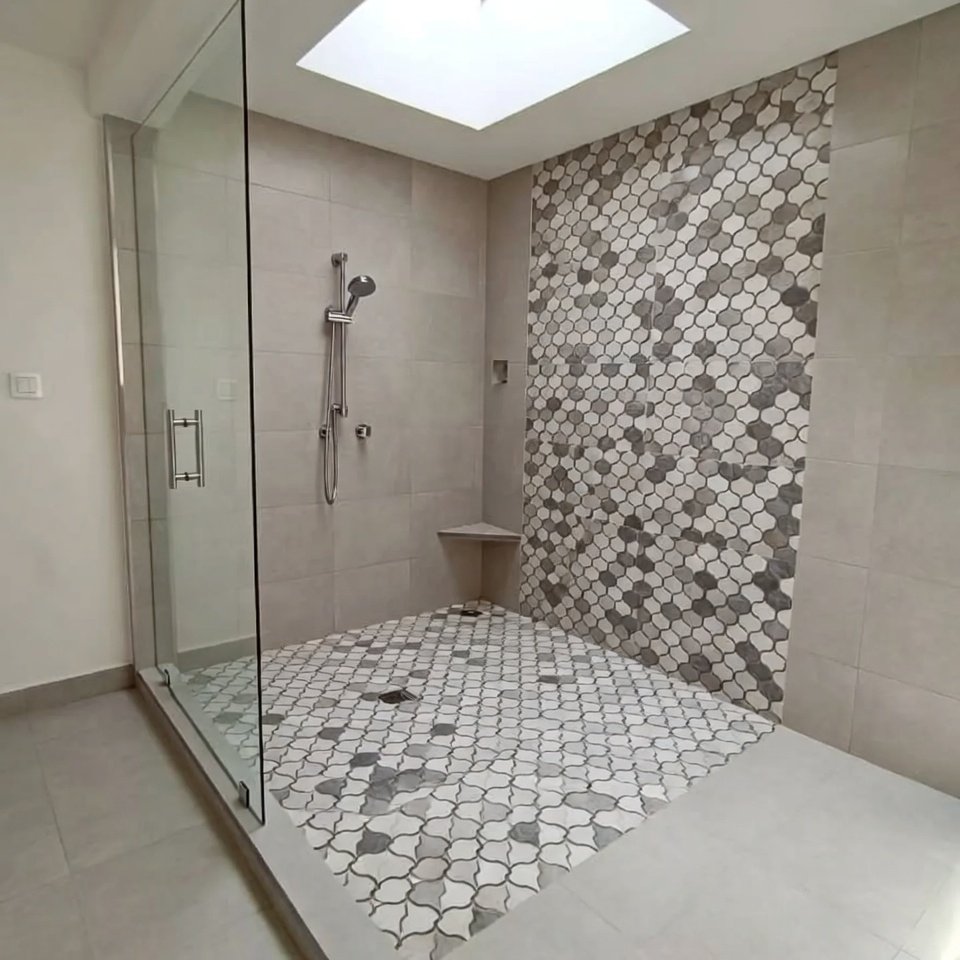 Bathroom with statement shower floor tiles featuring bold patterned tiles that stand out against neutral wall tiles.