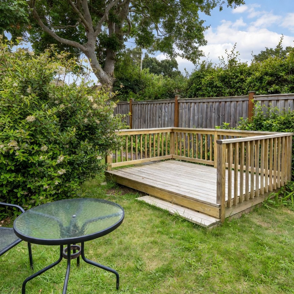 Backyard with wooden deck patio, outdoor seating, and surrounding greenery creating a warm outdoor living space.