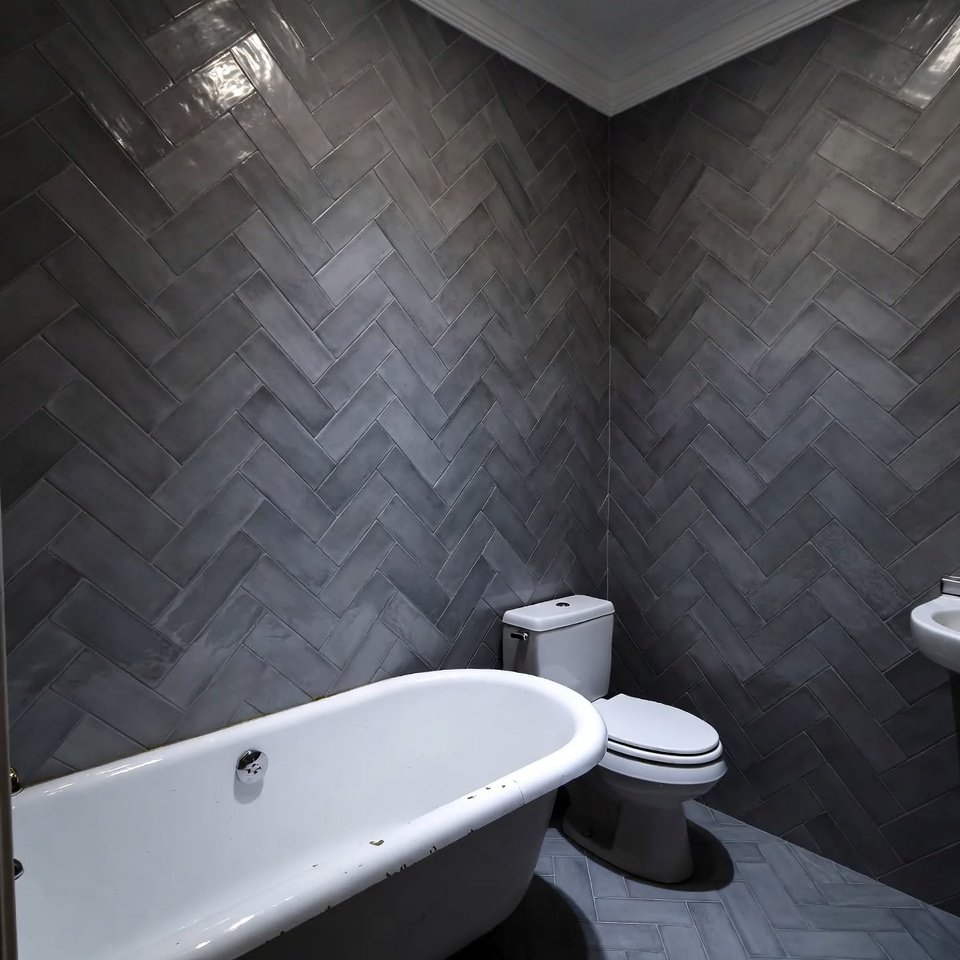 Bathroom wall with subway tiles arranged in a herringbone pattern, creating a textured and modern design behind the vanity.