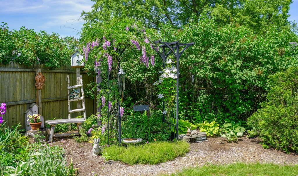Person planting flowers in a landscaped backyard garden bed with soil preparation and raised planting areas.