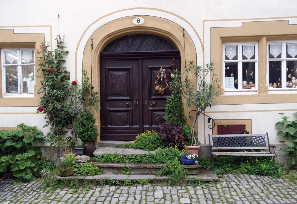 Front yard landscaping ideas in a USA home featuring a manicured lawn, shrubs, trees, flower beds, and a curved walkway leading to the entrance