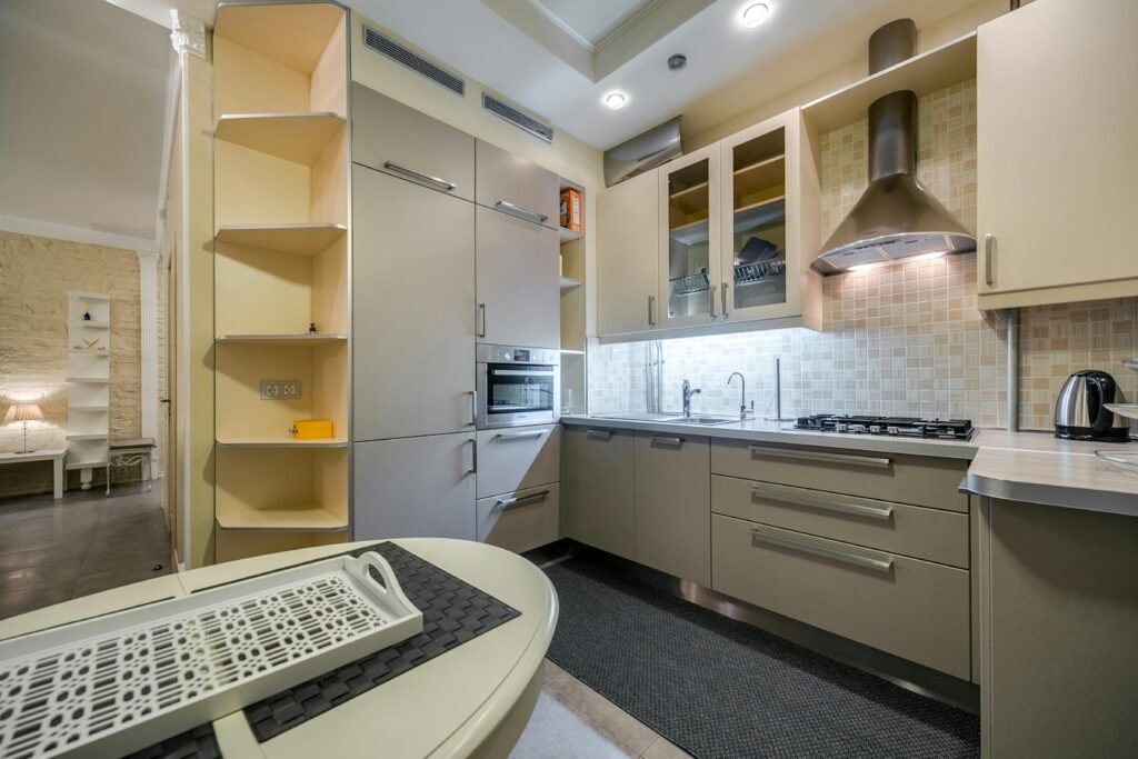 Bright modern kitchen with a kitchen range exhaust hood above the stove, light cabinetry, and a clean backsplash.