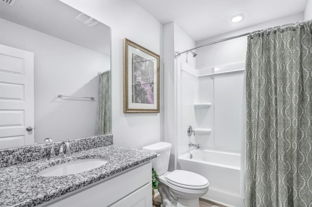 Compact bathroom with neutral shower curtain, tiled walls, and simple fixtures