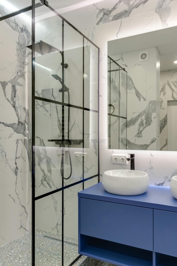 Minimalist bathroom with a frameless glass door for shower, matte fixtures, and neutral tiles