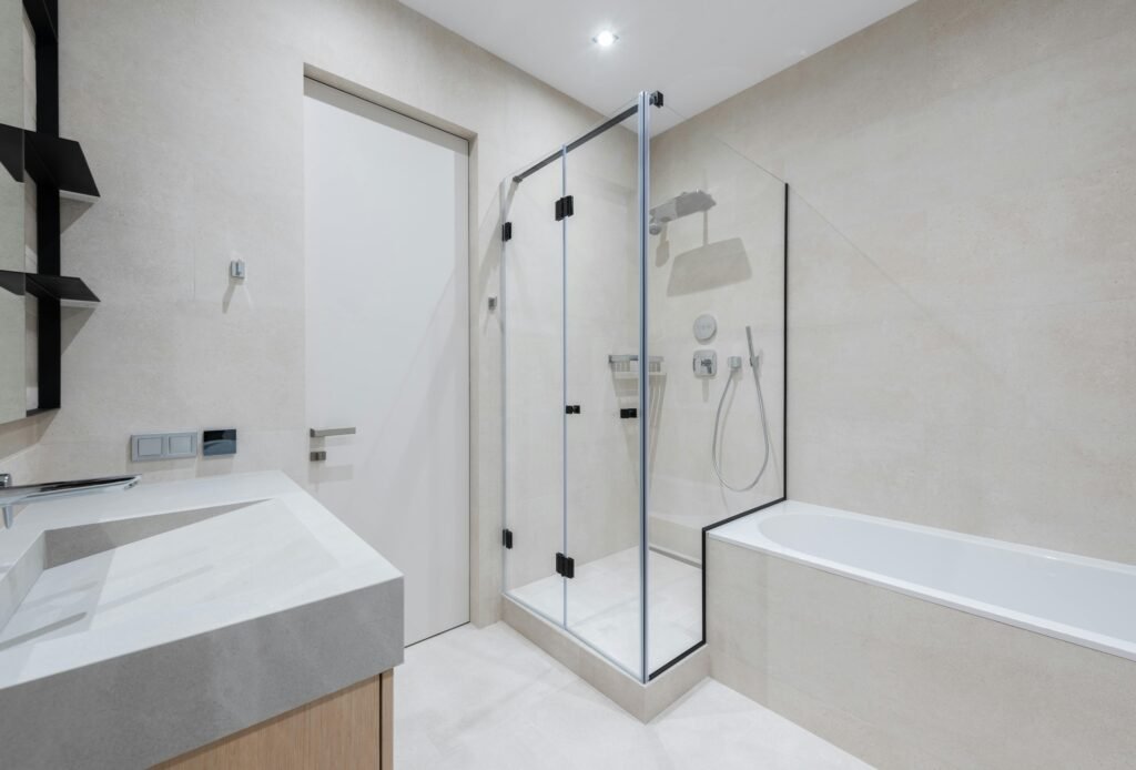 Modern bathroom with glass door for shower featuring clear frameless panels and sleek tile finish