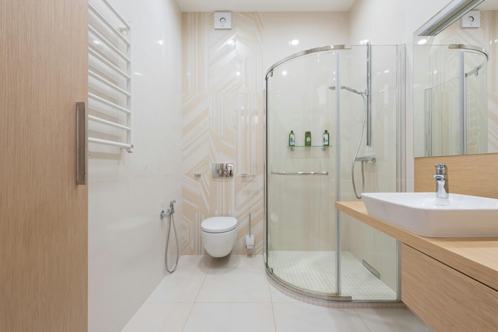 Minimalist bathroom with glass door for shower featuring frameless design and neutral tile walls