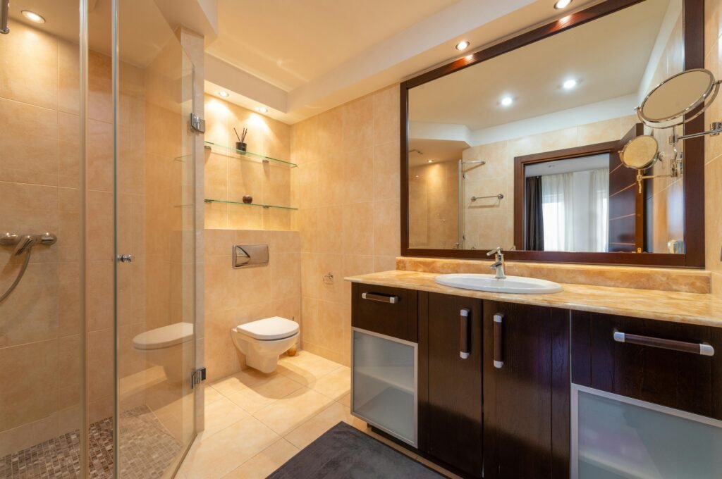 Elegant bathroom with glass door for shower featuring frameless panels and marble-style wall tiles