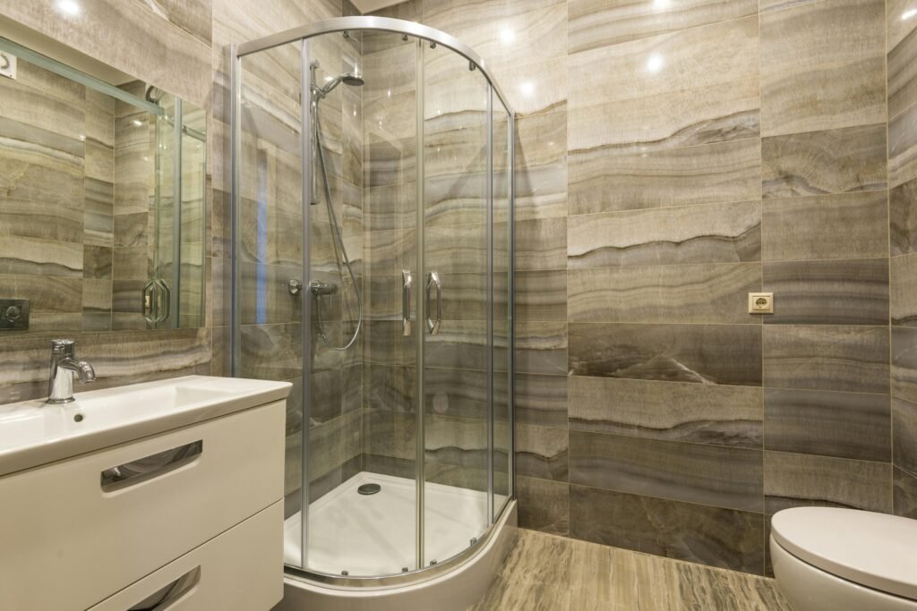 Luxury bathroom with glass door for shower featuring frameless design and elegant marble interior