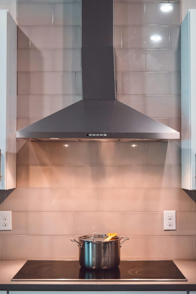 Minimalist kitchen with a kitchen range exhaust hood above the stove, sleek cabinets, and a clean modern layout.