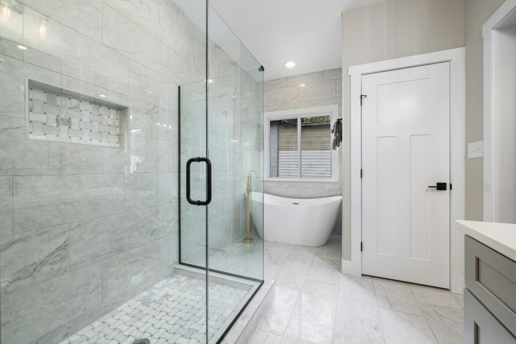 Spacious modern bathroom with glass door for shower featuring frameless enclosure and neutral tones