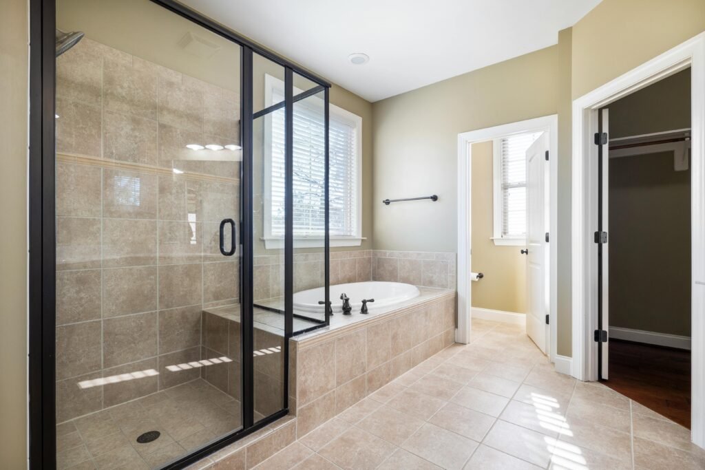 Bright bathroom with a hinged glass door for shower, white tiles, and a clean modern layout