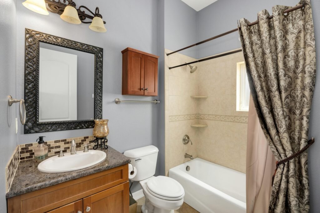 Light-filled modern bathroom with a textured shower curtain, glass window, and clean white tiles