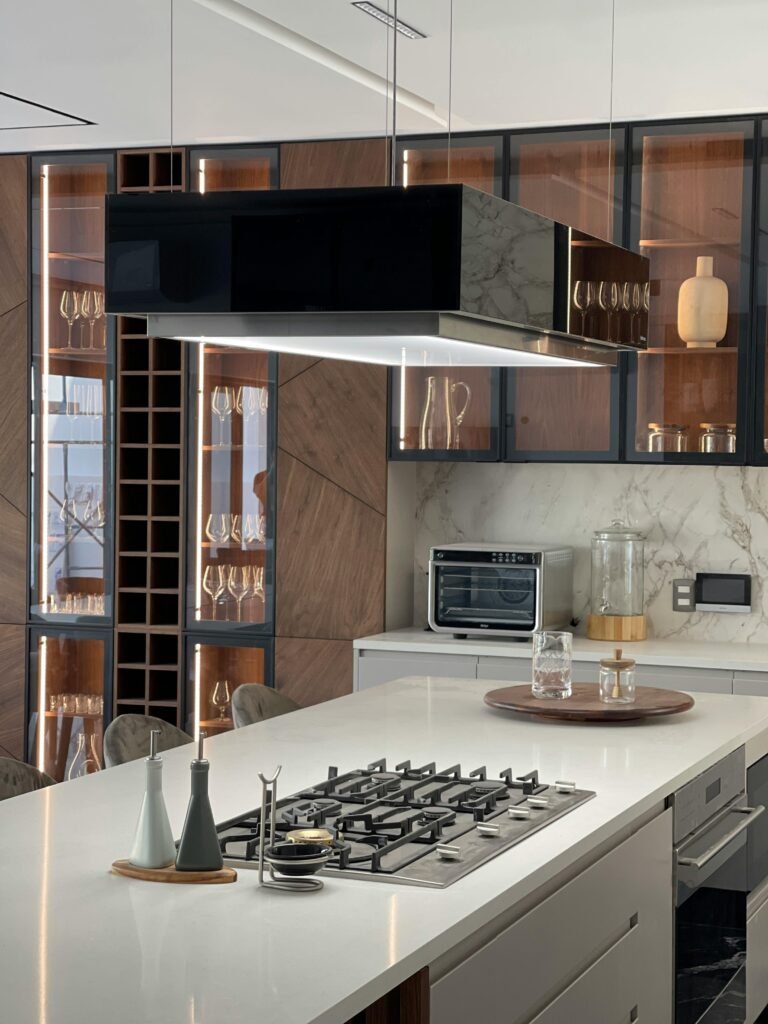 Modern kitchen with a kitchen range exhaust hood above the cooktop, light cabinets, and a bright, clean layout.