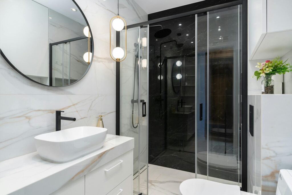 Contemporary bathroom with a tinted glass door for shower, dark tiles, and sleek modern fixtures