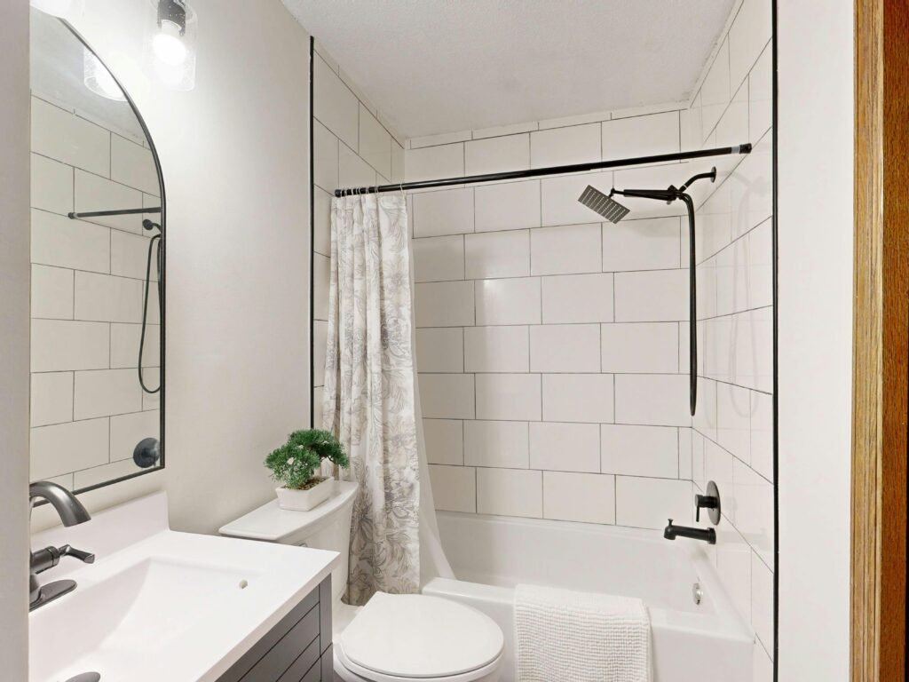 Spacious bathroom with light shower curtain, large tiles, and modern fixtures