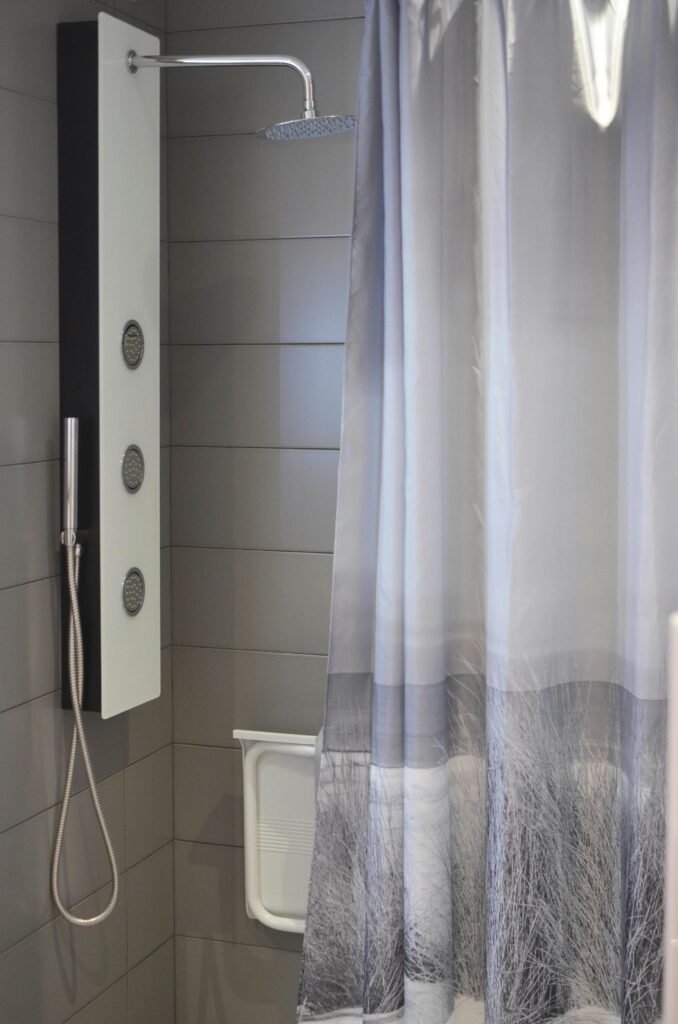 Minimal bathroom with light shower curtain, white tiles, and simple modern fixtures