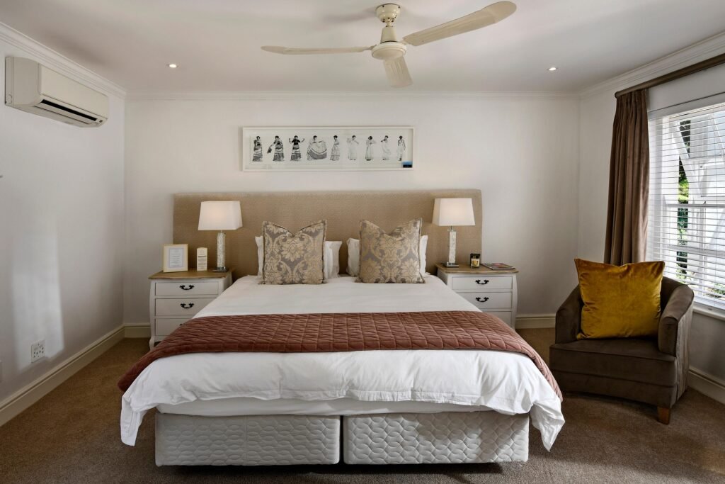 Modern master bedroom with cozy seating corner, featuring a comfortable armchair, soft lighting, neutral décor, and a relaxing contemporary design.