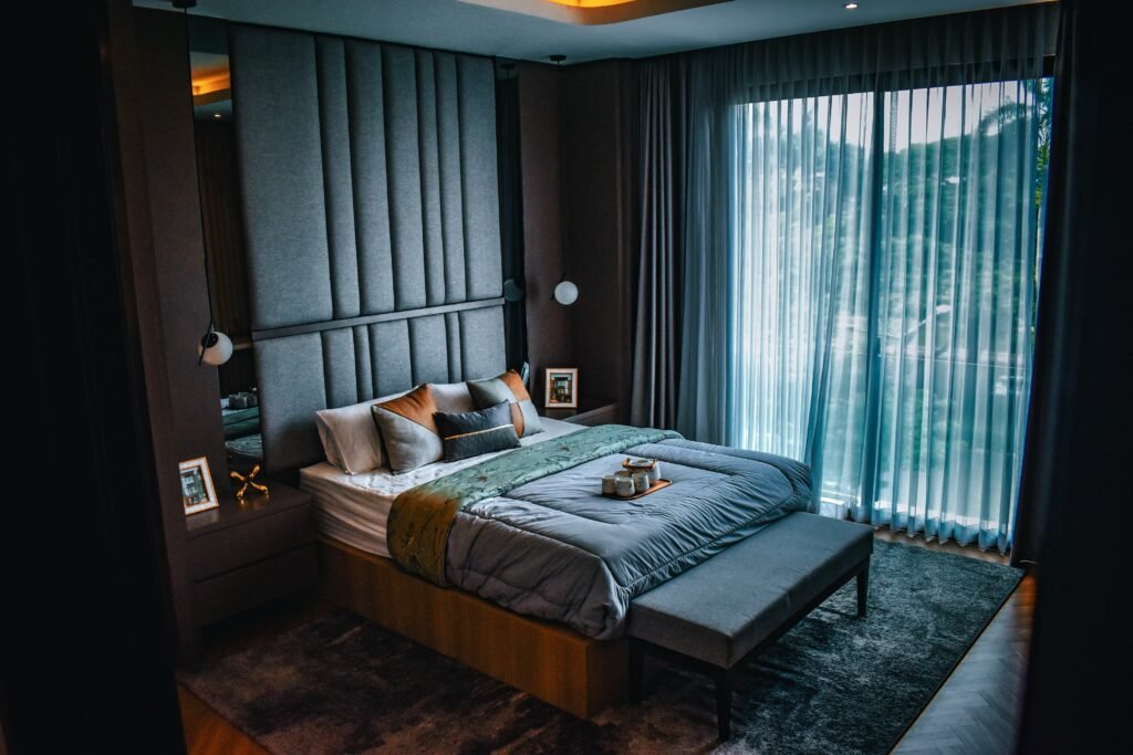 Modern master bedroom with an accent textured wall, featuring a stylish bed, layered bedding, warm lighting, and contemporary interior design.