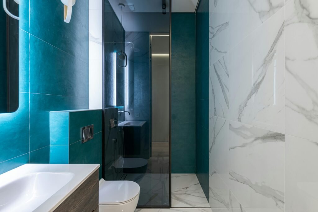 Modern bathroom featuring textured wall tiles, natural stone surfaces, wood accents, and layered materials for added visual interest.
