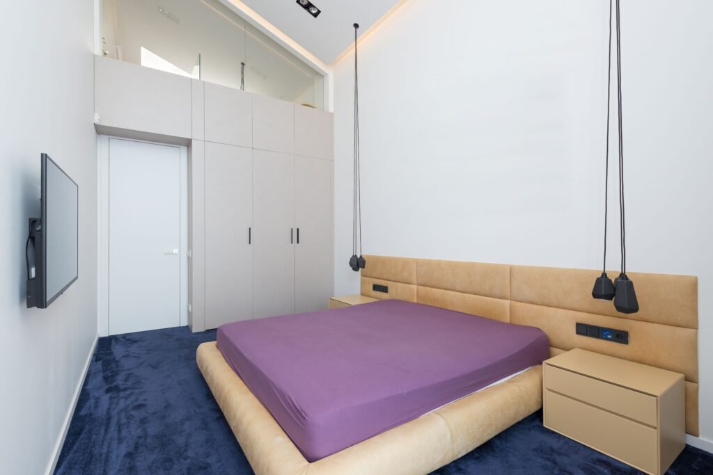 Modern master bedroom featuring a warm oversized headboard design, soft neutral bedding, elegant lighting, and contemporary furniture for a luxurious look.