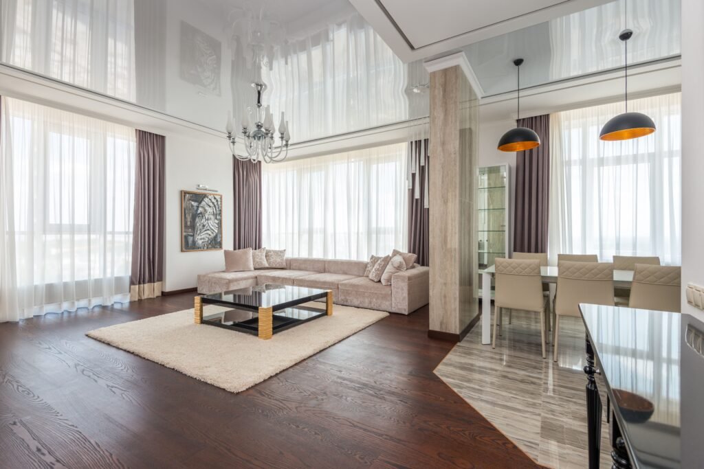 Warm and cozy living room featuring layered lighting, floor-to-ceiling curtains, large artwork, decorative mirrors, and textured rugs.