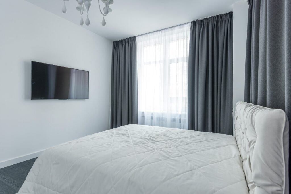 Affordable house in the USA featuring bedroom decorating ideas with curtains hung higher than the window, creating a spacious and elegant look.