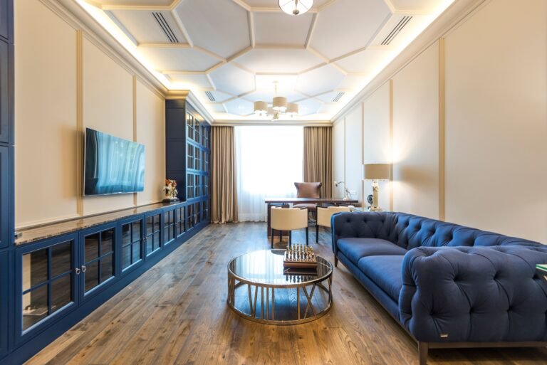Elegant coffered ceiling with recessed panels, decorative beams, crown molding, and modern lighting in a stylish living room.