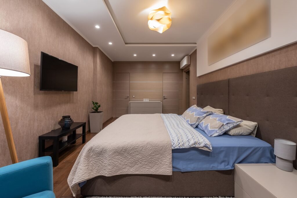 Modern master bedroom with layered lighting strategy, featuring ceiling lights, bedside lamps, ambient lighting, and a warm contemporary interior design.