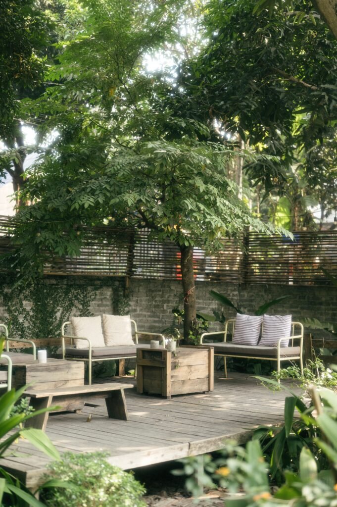 Composite deck extension connected to a landscaped backyard with mulch beds, shrubs, and decorative plants, featuring low maintenance backyard ideas without grass.
