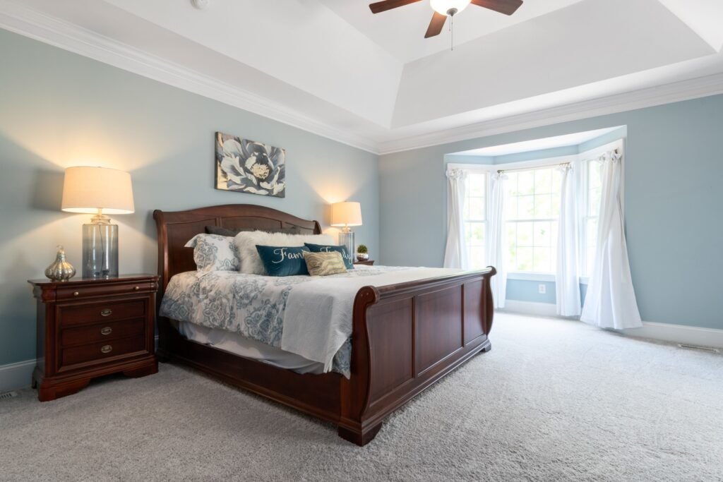 Modern master bedroom with floor-length curtains, featuring elegant drapes, soft natural light, neutral décor, and a contemporary interior design.