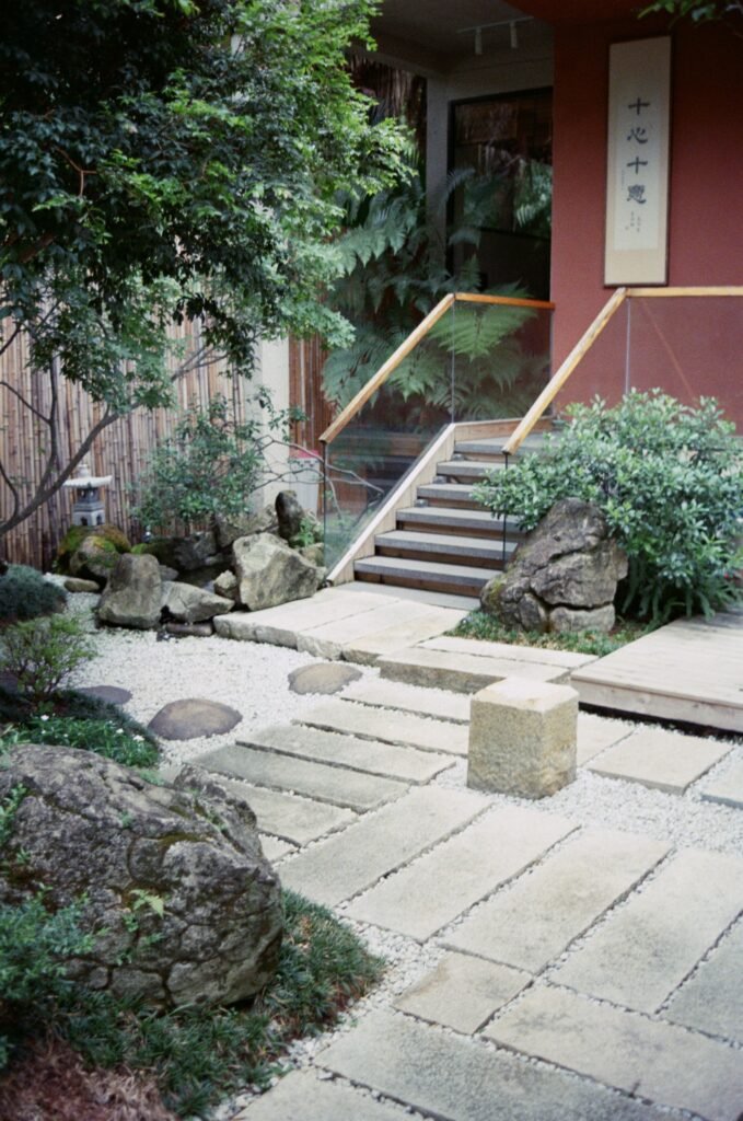 Low maintenance backyard ideas without grass featuring a Zen garden with raked gravel, natural stones, minimalist plants, and a serene outdoor seating area.