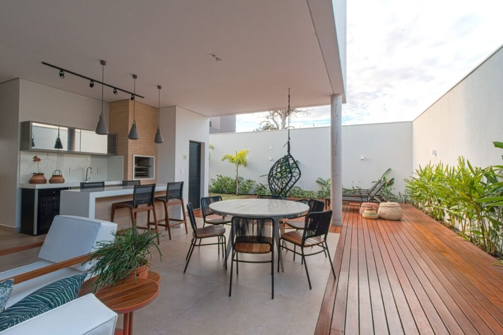 Low maintenance backyard ideas without grass featuring a modern outdoor kitchen area, paved patio, built-in grill, stylish seating, and easy-care landscaping.