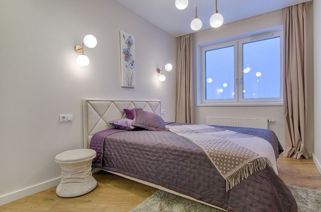 Modern master bedroom with wall lighting over lamps, featuring stylish bedside lamps, warm ambient glow, and contemporary interior design elements.