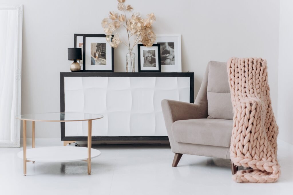 Warm and cozy living room featuring a comfortable chair, a small side table, a warm lamp, and a soft throw blanket.