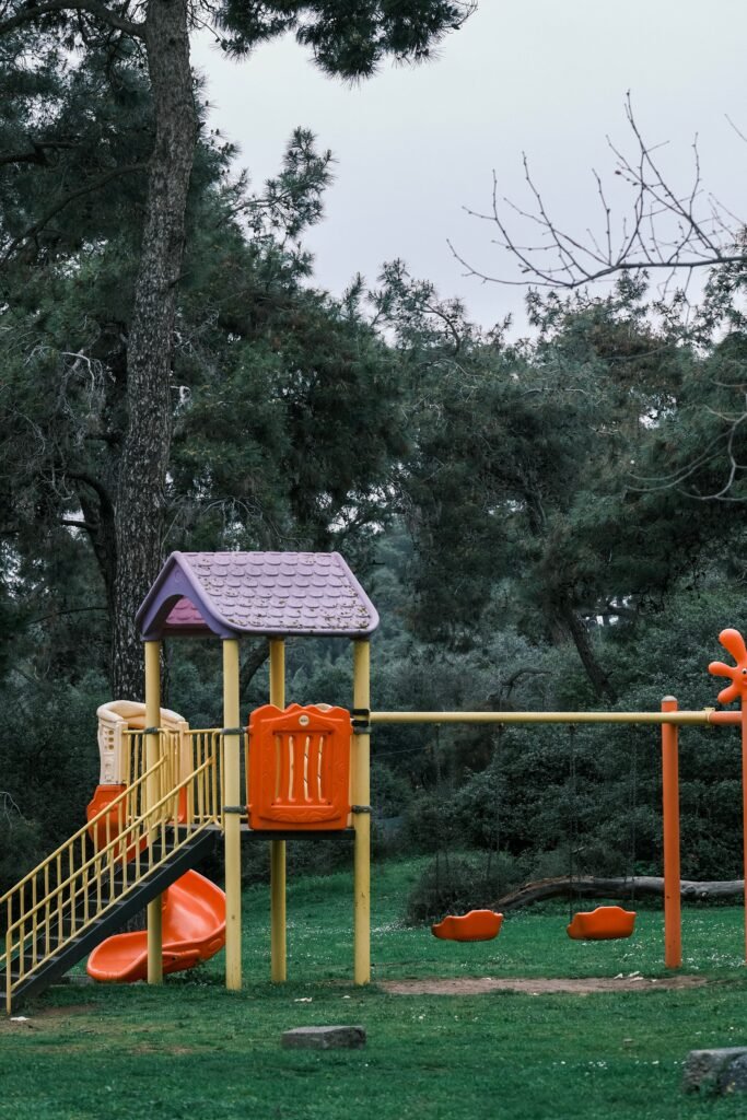 Low maintenance backyards without grass featuring a safe kids play area with rubber mulch, climbing structure, sandbox, and easy-care landscaping.