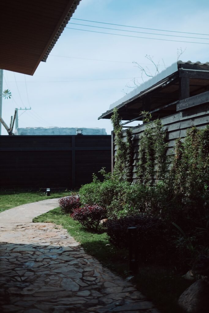 Stone pathways winding through mulched garden beds with shrubs, flowers, and decorative landscaping, featuring low maintenance backyard ideas without grass.