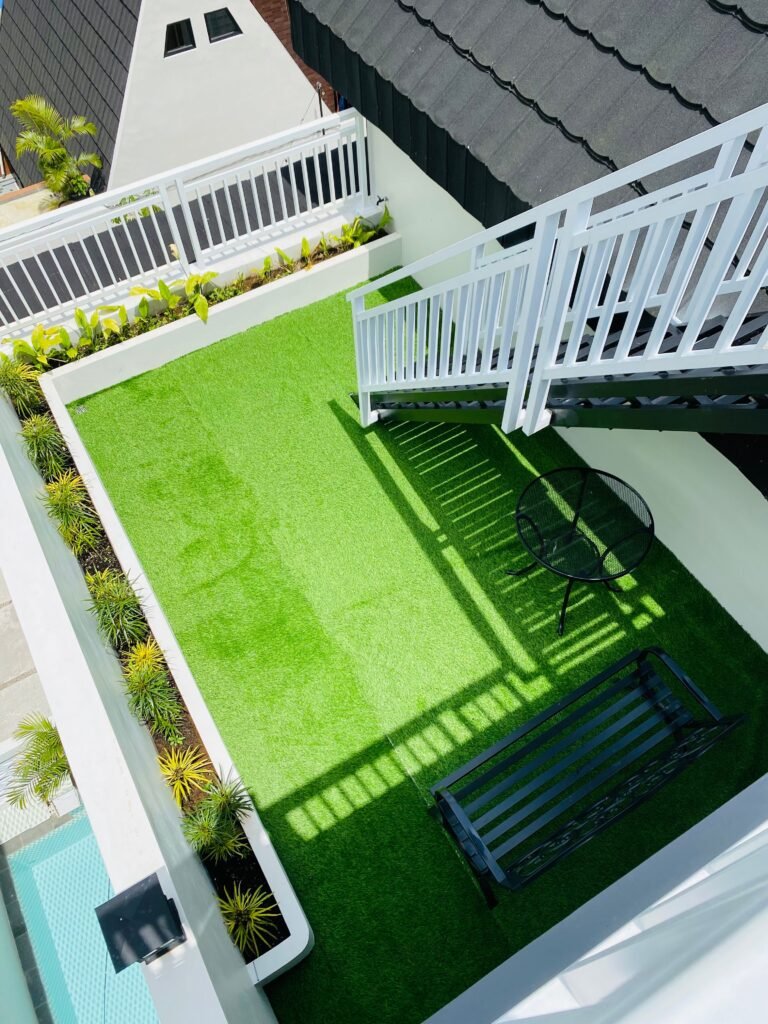 Low maintenance backyard ideas without grass featuring artificial turf, a modern patio area, decorative landscaping, and outdoor seating