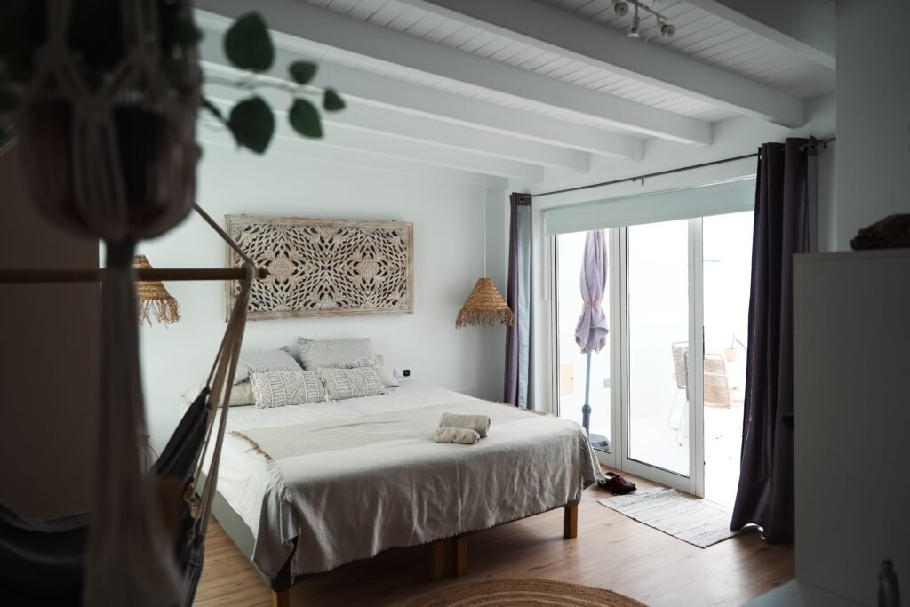 Modern master bedroom with warm neutral foundations, featuring beige walls, soft linen bedding, wooden furniture, and ambient lighting for a cozy atmosphere.