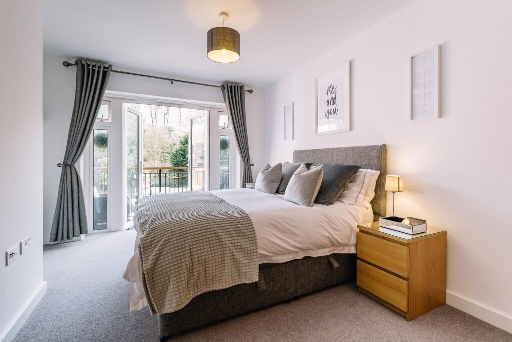 Modern master bedroom featuring a sleek platform bed frame, neutral decor, soft lighting, and contemporary furnishings for a sophisticated and relaxing retreat.